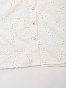 Close-up of white eyelet embroidery fabric and elegant buttons with gold rims on shirt