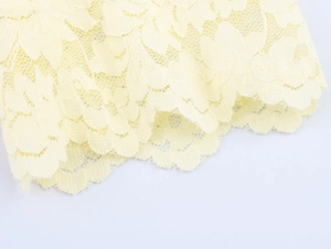 Vue macro d'un tissu de dentelle jaune clair avec motif floral délicat et structure en maille