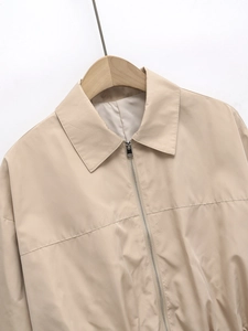 Close-up of lightweight beige jacket showing metal zipper and fine stitching detail