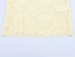 Détail du tissu en dentelle florale jaune avec bord festonné pour hauts d'été chic