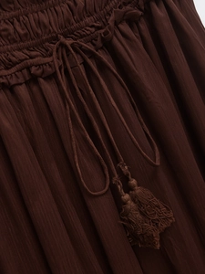 Detail of coffee brown elastic waist skirt with tassel drawstring and textured fabric