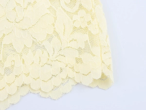 Gros plan sur un tissu en dentelle beige avec broderie florale et bordure ondulée