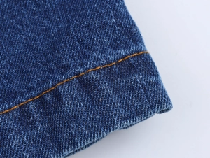 Macro shot of dark blue denim fabric with classic orange stitching and twill texture