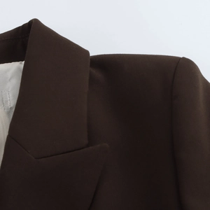 Détail du revers de blazer marron foncé avec coutures nettes et doublure grise rayée