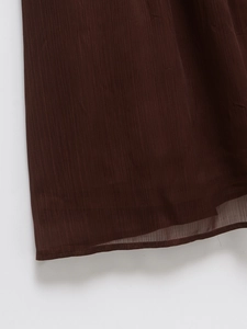 Detail view of burgundy chiffon skirt hem showing vertical texture and stitching