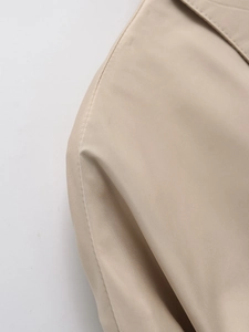 Close-up of shoulder stitching and fine weave texture on beige fashion jacket