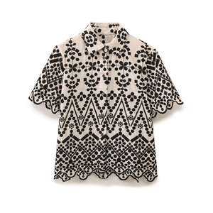 Detail of embroidered short sleeve shirt with scallop edges and geometric cutouts