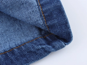 Detail of dark blue denim dress showing contrast orange stitching and twill texture