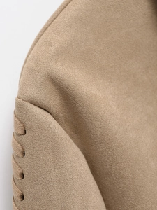 Detail of woven sleeve seam on khaki suede jacket showcasing soft fabric texture