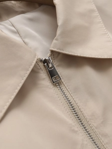 Close-up of lapel collar and silver metal zipper on stylish beige summer light jacket