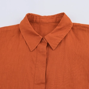 Détail du col et du bouton d'une chemise en lin orange avec texture de tissu naturel