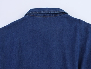 Macro detail of dark blue denim dress collar featuring classic orange contrast stitching