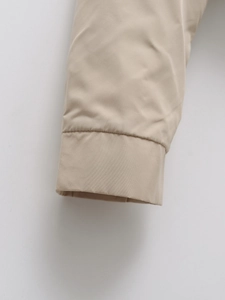 Close-up of neatly stitched cuff on lightweight beige jacket showing high-quality fabric texture