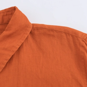 Détail de la texture du tissu orange et des coutures du col sur cette chemise d'été