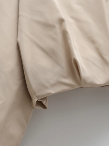 Macro shot of precise stitching and smooth khaki satin fabric on a casual summer jacket