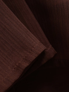Close-up of brown linen fabric showing fine weave texture and clean single-needle stitching
