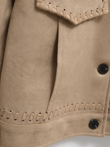 Detail of khaki suede jacket featuring braided trim, black buttons and soft texture