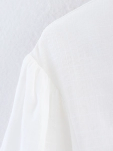Close-up of white long sleeve shirt showing cotton linen fabric texture and pleated shoulder detail