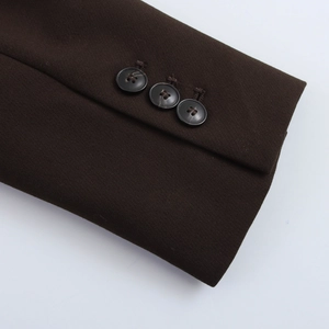 Détail de la manche du blazer marron foncé avec trois boutons noirs et texture tissée