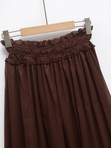 Detail of dark brown pleated skirt featuring elastic high waist with ruffled edge design