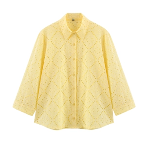 Detail of light yellow eyelet embroidery and hollow diamond pattern on shirt fabric