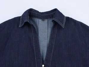 Détail du col d'une chemise en denim bleu foncé avec étiquette XS et coutures