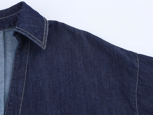 Détail d'une veste en denim bleu foncé avec surpiqûres et col à revers