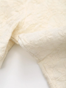 Close-up of intricate floral embroidery on cream cotton-linen summer set fabric