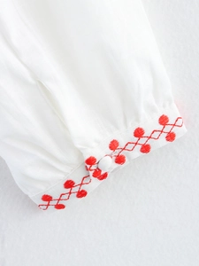 White linen shirt sleeve featuring red geometric flower embroidery and fabric buttons