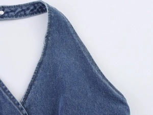 Detailed macro view of denim halter top featuring contrast stitching and metal button