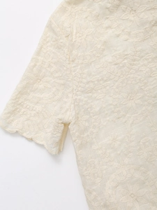 Detail of ivory cotton-linen shirt featuring floral embroidery and scalloped edge sleeves