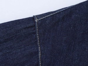 Détail des coutures jaunes contrastées et de la texture sergé sur denim bleu foncé