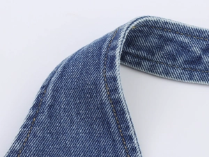 Detailed macro view of dark blue washed denim fabric with yellow contrast stitching