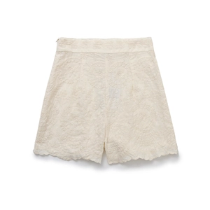 Close-up of cream high-waisted shorts with floral embroidery and scalloped edges