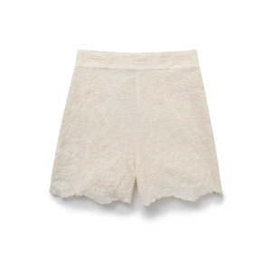 Close-up of high-waist cream shorts with floral embroidery and scalloped edges