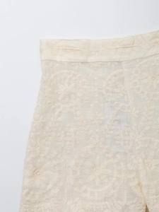 Detailed close-up of cream cotton-linen shorts with intricate circular floral embroidery