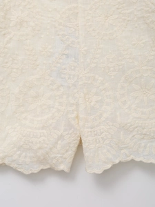 Detail of scalloped hem with floral embroidery on summer linen-style shirt and shorts