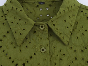 Close-up of grass green shirt featuring delicate hollow embroidery and resin button detail