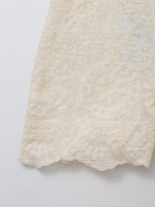 Detailed close-up of cream floral embroidery and scalloped edge on summer shorts set