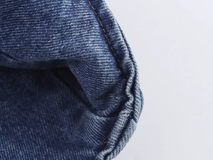 Close-up of dark blue denim stitching detail with yellow thread on a high-quality fabric