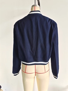 Rear view of a navy blue cropped varsity jacket with white striped ribbed collar and hem