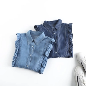 Casual ruffled denim shirts in light and dark blue wash laid flat on white backdrop