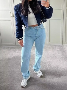 Detail of navy blue cropped varsity jacket paired with high-waisted light blue jeans