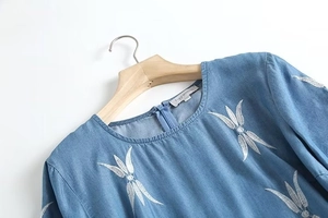 Détail de la broderie de feuilles et de la fermeture éclair cachée sur la robe en jean