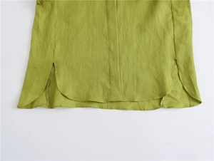 Close-up of curved hem and side slit detail on light green linen casual blouse