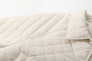 Close-up of quilted cream jacket showing lapel collar detail and high-quality stitching