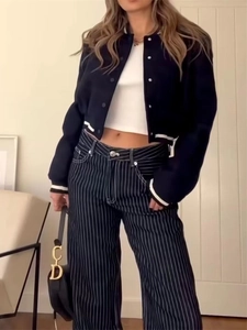Close-up of a navy short baseball jacket with white stripes and slim cropped white top