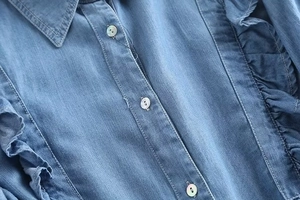 Close-up of ruffle details and pearlescent buttons on a vintage blue denim shirt