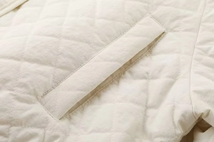 Detailed close-up of diamond quilted pattern and side pocket on the cream shirt jacket