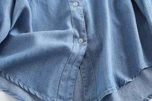 Detail of light blue denim shirt showing front buttons and fine fabric texture